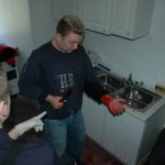 Verletztensitutation in der Küche: eine Person hat sich beim Brotschneiden in den linken Unterarm geschnitten.