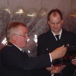 Ein Dankeschön an die Jubilare von den Kameraden der Wehr: ein in Glas gebranntes Bild des Feuerwehrhauses Curslack. Thomas Hitscher nimmt das Geschenk von Wehrführer Werner Meyer entgegen.