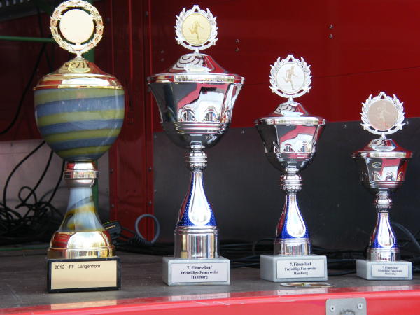 Darum ging es: links der gr. Wanderpokal, rechts die Pokale für die Plätze 1 - 3. Außerdem Gutscheine für Sportanschaffungen von 100-300 €. (c) AG MuK FF HH