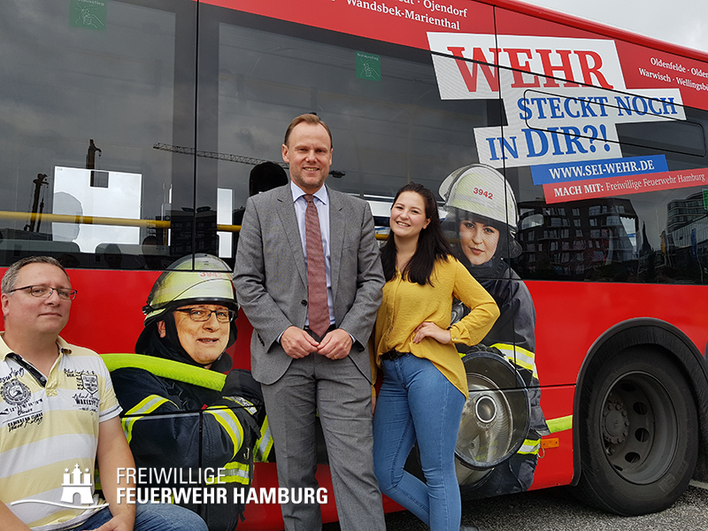 Innensenator Andy Grote zusammen mit 2 Protagonisten, die auf den Bussen mit abgebildet sind.